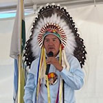 Bobby Cameron se tient debout avec un microphone lors d'un événement communautaire dans la Star Blanket Cree Nation.