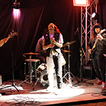 Un chanteur de métal accompagné de son groupe sous le chapiteau extérieur.