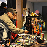 Un couple de visiteurs regardant des bijoux fabriqués à la main.